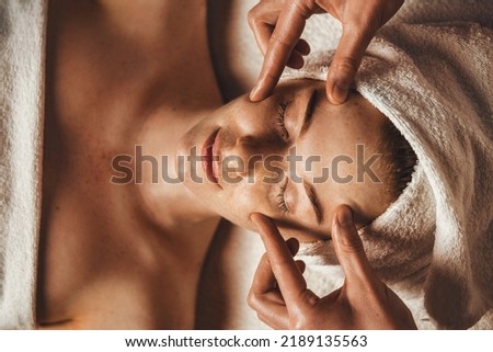 Top view of young woman getting spa massage treatment at beauty spa salon. Face massage. Spa skin and body care.