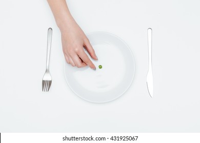 Top View Of Young Woman Hand Taking One Green Pea From The Plate Over White Background