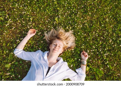 Top View Of A Young Woman Lying On A Meadow With Blooming Clover With Closed Eyes. Insects, Allergies, Spring Mites