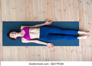 Top View Of Young Woman Lying In Corpse Or Dead Body Pose Relaxing After Practicing Yoga