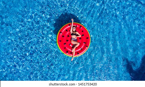 Top view of young woman relaxing on watermelon lilo in villa resort pool - Rich girl floating with fruit mattress drinking tropical cocktail - Summer holiday, luxury lifestyle and fashion concept