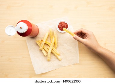 Top view of youngwoman dipping french fried  with tomato sauce ( ketchup ) on wood table background.Fast food and healthy concepts ideas - Powered by Shutterstock