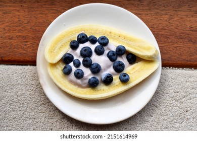 Top viewed of combination between sliced ripe banana and blueberry and yogurt on white plate, delicious and healthy food style for breakfast time.