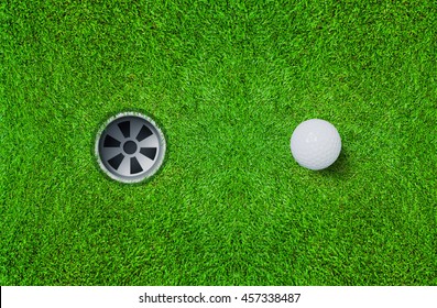 Top views of golf ball and golf hole on green grass texture background.