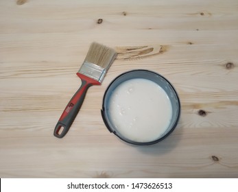 Top Wiev. A Pail Of Lacquer On Wood And A Brush On The Table