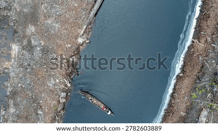 A top-down aerial perspective captures a winding natural blackwater stream meandering irregularly through a recovering, degraded peatland landscape, showcasing natural hydrological pathways essential for carbon sink preservation.