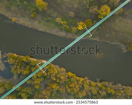 A top-down aerial view of a bridge spanning the Morava River, surrounded by vibrant autumn foliage. The bridge’s structure contrasts with the natural landscape below.