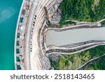 Top-down aerial view of Enguri dam in Georgia with reservoir and water flow visible. Massive concrete structure and surrounding landscape demonstrate scale of this hydropower project