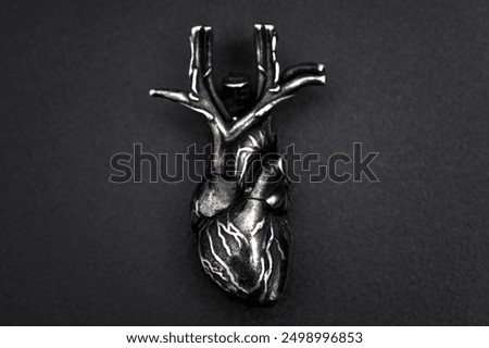 Top-down close-up view of an intricate heart model positioned against a dark background, highlighting detailed vascular structures. Suitable for medical illustration and educational use.