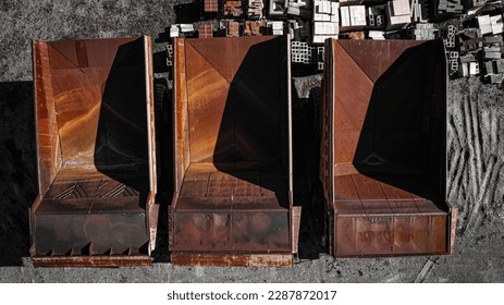 Top-down drone shot of three rusted, abandoned dump trucks, shadows casting on their decaying forms, alluding to the stories of their once powerful past.