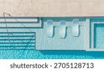 Top-down image of a luxury pool featuring built-in loungers, shimmering water, and elegant step design.