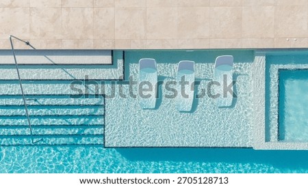 Top-down image of a luxury pool featuring built-in loungers, shimmering water, and elegant step design.