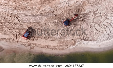 Top-down perspective of heavy machinery performing coastal management and sand replenishment on an Australian shoreline.