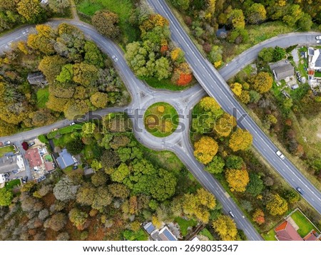 Top-down perspective of a traffic circle and overpass with vibrant autumn trees