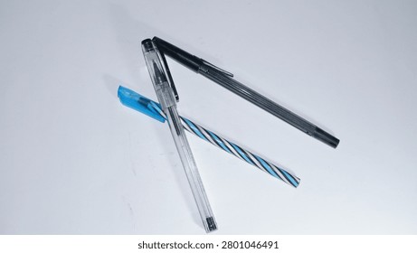 A top-down shot of three various plastic ballpoint pens arranged neatly against a clean white background, perfect for school, office, and stationery concepts.