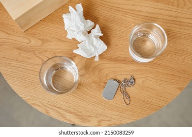 Top-down Still Life Shot Of Used Paper Napkins, Glasses With Water And Military Dog Tag On Table, PTSD Treatment Concept