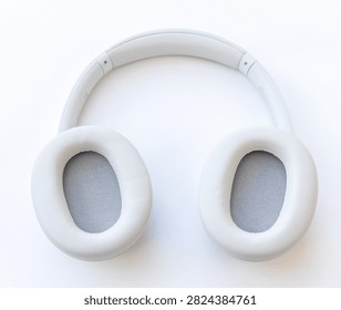 A topdown studio shot of modern light gray overear wireless headphones resting on a clean white background