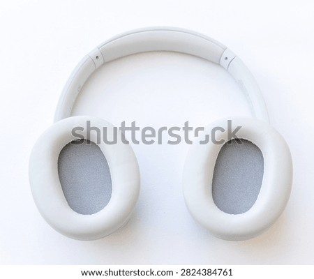 A topdown studio shot of modern light gray overear wireless headphones resting on a clean white background