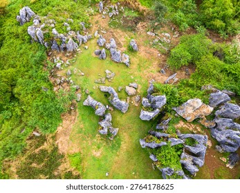 Top-down view of ancient rock formations scattered across green fields. Unique geological karst landscape with weathered limestone boulders, at Stone Garden, Padalarang, Bandung, Indonesia.