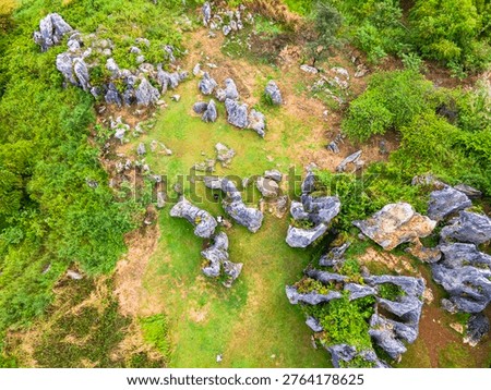 Top-down view of ancient rock formations scattered across green fields. Unique geological karst landscape with weathered limestone boulders, at Stone Garden, Padalarang, Bandung, Indonesia.