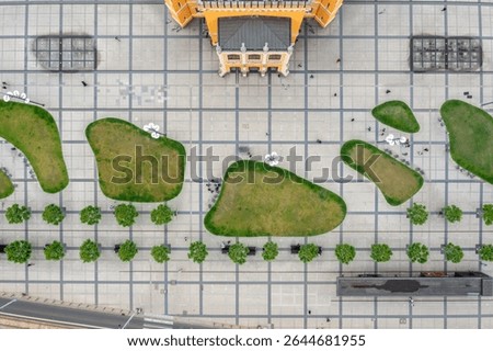 Top-down view of architectural square with green patches and walking pedestrians in modern public space