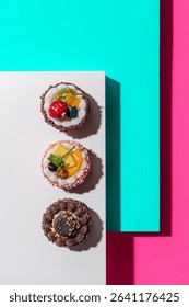 Top-Down View of Assorted Mini Cakes on Aqua and Pink Background