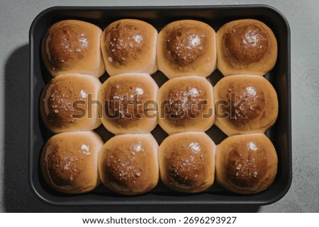 A top-down view of a baking pan containing golden-brown dinner rolls