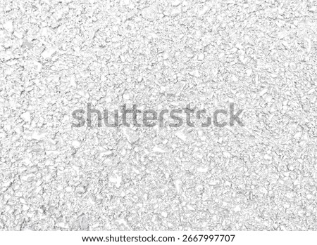 A top-down view of a coarse, textured surface, possibly asphalt or concrete. The image is filled with small, jagged fragments of various shades of light gray and white, creating a rough and grainy
