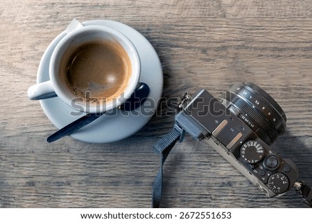 A top-down view of a coffee cup and camera on a wooden table, conveying creativity, relaxation, and artistic pursuits in a cozy, content atmosphere.
