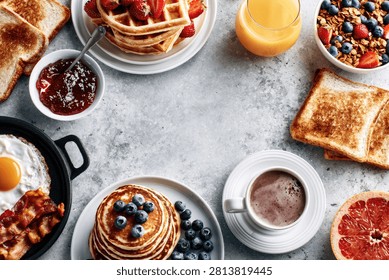 A top-down view of a delightful breakfast spread featuring pancakes, waffles, fried eggs, bacon, toast, and coffee.