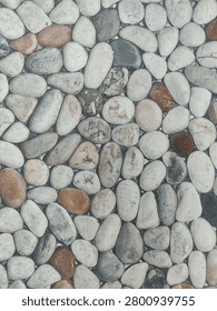 top-down view of a densely packed surface made of smooth, rounded river pebbles or stones. 