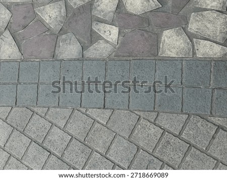 Top-down view of different stone paving styles, featuring irregular flagstones and arched cobblestone patterns in shades of grey and muted purple.