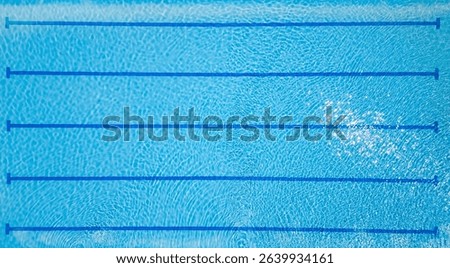 Top-down view of an empty swimming pool with lane dividers and clear blue water. Sunny reflections and clean geometry make it perfect for fitness, sports, and summer themes.