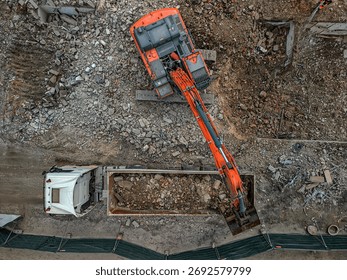 Top-down view of an excavator loading debris into a large truck at the demolition site in Gdansk, Poland, showcasing the efficiency of the industrial machinery in rubble clearance