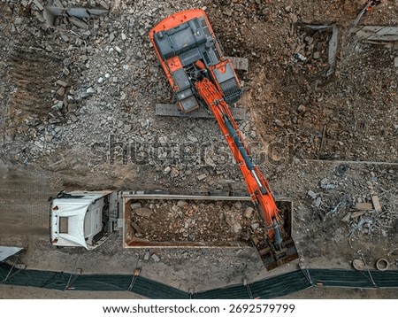 Top-down view of an excavator loading debris into a large truck at the demolition site in Gdansk, Poland, showcasing the efficiency of the industrial machinery in rubble clearance