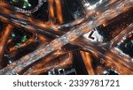 Top-down view of fast-moving cars on a highway, intense traffic during rush hour at a city crossroad, modern multi-level intersection with beautifully moving vehicles.