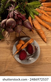 Top-down view of a kitchen table with a variety of fresh beets and carrots neatly arranged on the surface