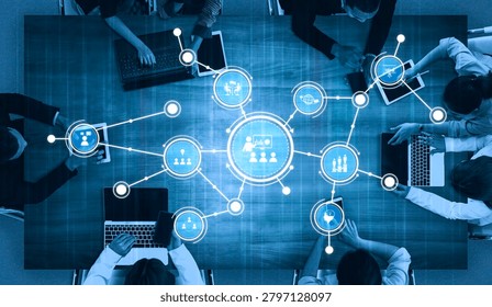 A top-down view of a modern workspace showcasing professionals engaging with technology. Digital elements highlight connectivity and collaboration in a team setting. Tessel