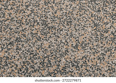 Top-down view of a multi-colored aggregate stone texture. High-quality background featuring tan and black speckled details.