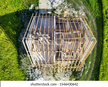 Top-down View On Detached House Under Construction Rounded By Green Grass. In Small Village. Building Materials Around. Aerial Photo, Taken In Poland In 2019.