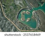 Top-down view on the salt-marsh area with lales, with wooden boardwalks and trails for walking and birdwatching. Alvor, Portugal