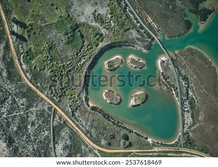 Top-down view on the salt-marsh area with lales, with wooden boardwalks and trails for walking and birdwatching. Alvor, Portugal