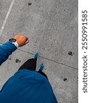 A top-down view of a person in a blue athletic outfit, wearing a white smartwatch and blue sneakers, walking on a textured concrete surface. The image highlights movement and an active lifestyle.