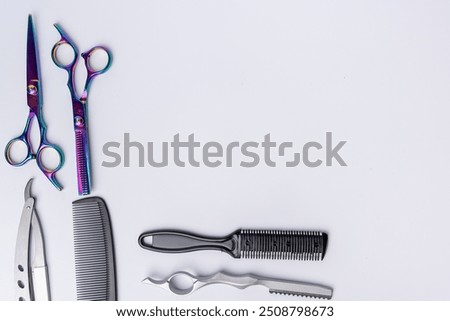 A top-down view of professional barber tools neatly arranged on the left and bottom of a white background. Perfect for showcasing grooming essentials and barbering equipment.