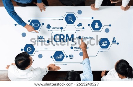A top-down view of a professional team collaborating on a customer relationship management strategy, featuring an interactive diagram illustrating connections and icons. Amity