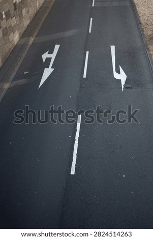Top-down view of a road marked with left and right directional arrows, symbolizing navigation, choice, traffic guidance, transportation, decision making, and route planning.