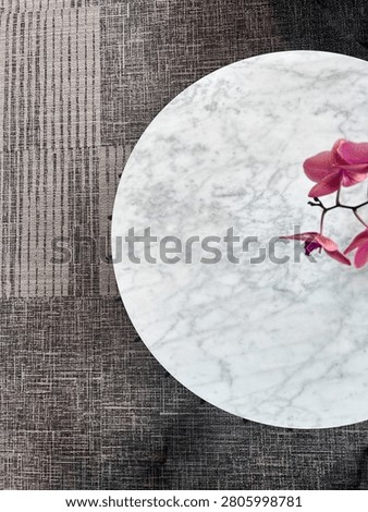 Top-down view of a round white marble coffee table with a pink orchid flower.