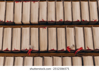 top-down view of rows of old books with worn pages and red bookmarks, neatly arranged on wooden shelves. Warm, cozy lighting.