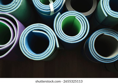 Top-down view of several rolled exercise mats arranged on a neutral background. Minimalist composition, suitable for fitness, wellness, yoga, and home workout concepts.