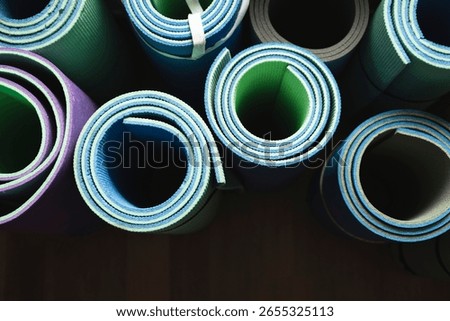 Top-down view of several rolled exercise mats arranged on a neutral background. Minimalist composition, suitable for fitness, wellness, yoga, and home workout concepts.